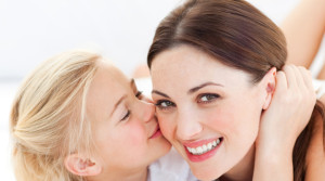 Close-up of a blond little girl kissing her mother