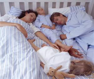 Parents and two children sleeping in bed