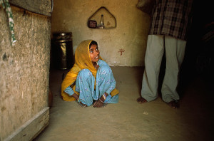 A child bride cowers at her husband's feet